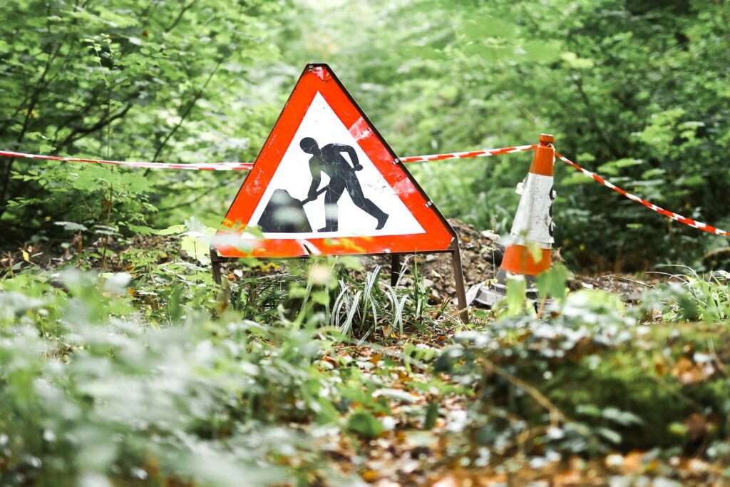 A road work sign in a forest setting in Ironbridge, UK, indicating an ongoing construction project amidst lush surroundings.
